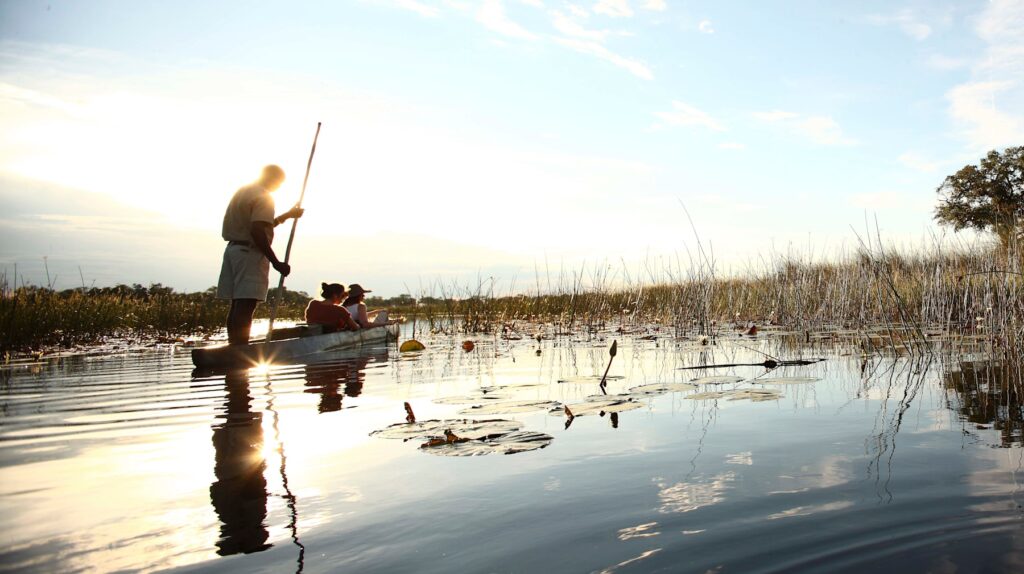A mokoro glides through the Okavango Delta at sunrise near &Beyond Xaranna